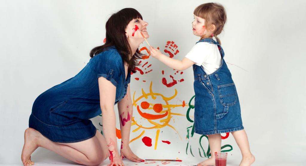 девочка рисует на щеке мамы