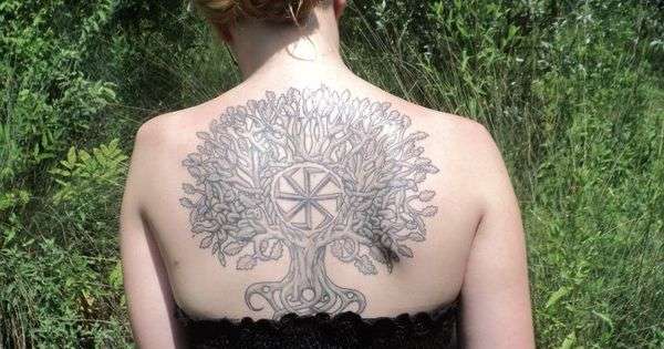 татуировка коловрат и древо на спине у девушки